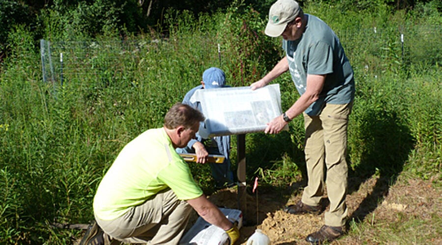 Volunteers install a sign at JK Black Oak