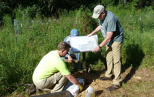 Volunteers install a sign at JK Black Oak